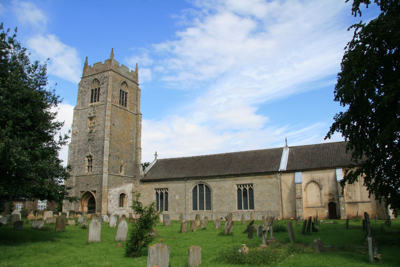 St Mary's parish church at Holme-next-the-Sea, a flint church with a square west tower, seen across its churchyard.